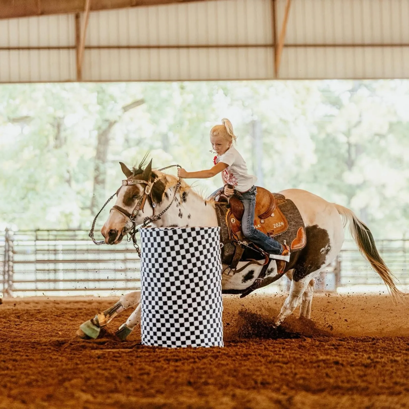 A barrel racer on a paint horse rounding a barrel at the Sabine County Rodeo